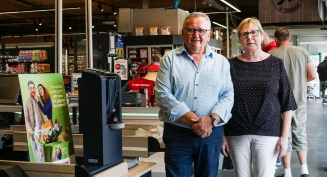 Michel en Nadine Ronse van Intermarché Doornik poseren trots naast het nieuwe, gesloten kasverwerkingssysteem