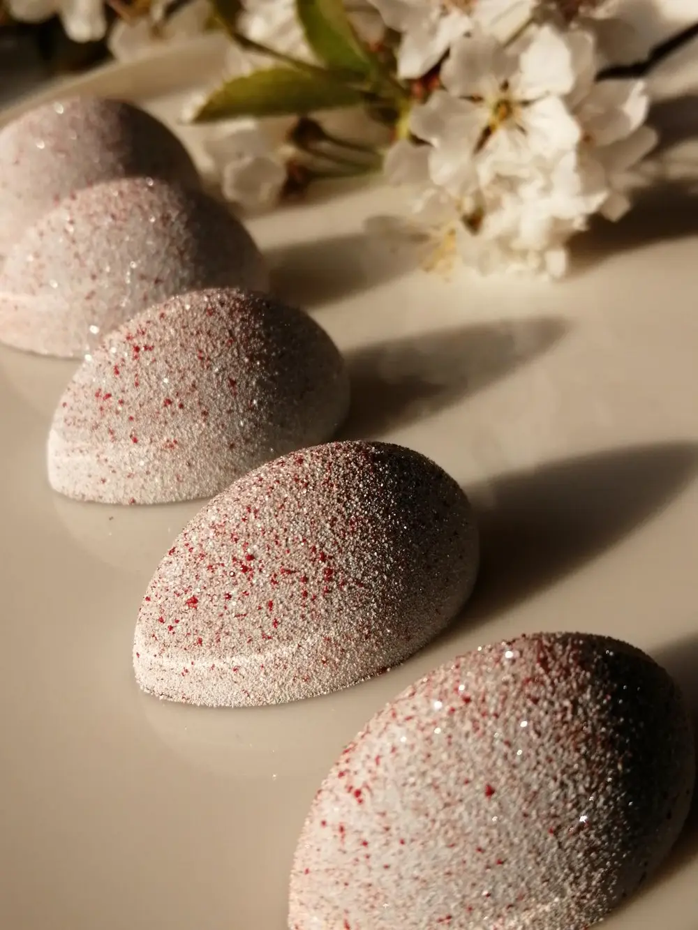 Interne opbouw Onderaan vinden we een crunch van sesam met cashewnoot, gevolgd door een crème van kers. De toplaag is een creamy gel van limoen met saffraan. Om deze laatste te bekomen maakte ik geen gebruik van een traditionele toevoeging zoals agar-agar, gelatine,... en toch werd het gewenste resultaat bereikt.  Zout, zuur, zoet….alles komt aan bod en is in balans met elkaar. De vullingen zijn complementair, geen enkele dominant, en bovendien heeft elk van hen een andere structuur. De extra\'s die erbij worden gegeven maken het geheel af en zorgen voor een extra smaak, umami. De chocolade die werd gebruikt is een Venezolaanse donkere chocolade. Op deze manier komt ook het bittere, kruidige en fruitige naar boven.  Coating Ik heb niet gekozen voor een glanzende buitenkant, maar voor een matte/velours coating. De kleuren zijn een ode aan de kleuren van de Japanse vlag, alsook aan de kersenbloesem die we in de dip terugvinden. De coating werd aangebracht met de airbrush.   Decoratie De dip en gomashio die erbij worden geserveerd maken het geheel af, en zorgen voor een verrassende wending. Zo bekomen we een elegante praline met een extra dimensie.  De dip is gebaseerd op de Japanse saus ‘Tonkatsu’. Echter, kersenbloesem, symbool voor Japan, mocht in dit geheel niet ontbreken en werd dus mee in deze dip verwerkt. De gomashio zorgt nog voor een extra crunchy toets. Just dip it!  Concept Less is more, de chopsticks en 2 toevoegingen, zijn een leuke twist en laten de praline toch nog de hoofdrol spelen. Pralines eten wordt door deze extra’s een beleving, iets uniek en ongezien.  De benaming, JUST DIP IT spreekt voor zich. Deze eerste versie, \'Sushi style\', kan gevolgd worden door tal van varianten. Old school, the African way, the crazy one,….om maar enkele voorbeelden te noemen. Elke variant kan worden voorzien van een bijhorende dip en een leuke twist.  JUST DIP IT!!