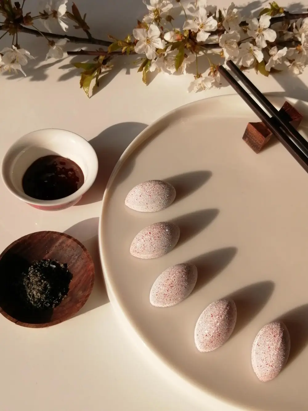 Interne opbouw Onderaan vinden we een crunch van sesam met cashewnoot, gevolgd door een crème van kers. De toplaag is een creamy gel van limoen met saffraan. Om deze laatste te bekomen maakte ik geen gebruik van een traditionele toevoeging zoals agar-agar, gelatine,... en toch werd het gewenste resultaat bereikt.  Zout, zuur, zoet….alles komt aan bod en is in balans met elkaar. De vullingen zijn complementair, geen enkele dominant, en bovendien heeft elk van hen een andere structuur. De extra\'s die erbij worden gegeven maken het geheel af en zorgen voor een extra smaak, umami. De chocolade die werd gebruikt is een Venezolaanse donkere chocolade. Op deze manier komt ook het bittere, kruidige en fruitige naar boven.  Coating Ik heb niet gekozen voor een glanzende buitenkant, maar voor een matte/velours coating. De kleuren zijn een ode aan de kleuren van de Japanse vlag, alsook aan de kersenbloesem die we in de dip terugvinden. De coating werd aangebracht met de airbrush.   Decoratie De dip en gomashio die erbij worden geserveerd maken het geheel af, en zorgen voor een verrassende wending. Zo bekomen we een elegante praline met een extra dimensie.  De dip is gebaseerd op de Japanse saus ‘Tonkatsu’. Echter, kersenbloesem, symbool voor Japan, mocht in dit geheel niet ontbreken en werd dus mee in deze dip verwerkt. De gomashio zorgt nog voor een extra crunchy toets. Just dip it!  Concept Less is more, de chopsticks en 2 toevoegingen, zijn een leuke twist en laten de praline toch nog de hoofdrol spelen. Pralines eten wordt door deze extra’s een beleving, iets uniek en ongezien.  De benaming, JUST DIP IT spreekt voor zich. Deze eerste versie, \'Sushi style\', kan gevolgd worden door tal van varianten. Old school, the African way, the crazy one,….om maar enkele voorbeelden te noemen. Elke variant kan worden voorzien van een bijhorende dip en een leuke twist.  JUST DIP IT!!