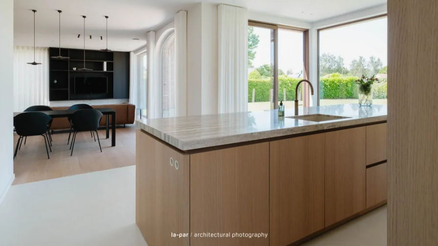 De combinatie van warm eikfineer en travertin geeft de keuken een rustige, tijdloze uitstraling