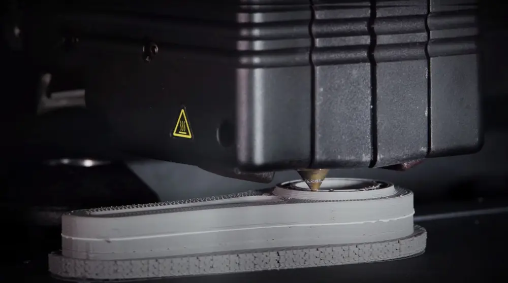 DM Studio System 2 print laagsgewijs een mix van bindmiddel, wax en een metaalpoeder, en print ook een keramische laag (wit) tussen het onderdeel en de steun die het na sinteren mogelijk maakt om deze makkelijk van elkaar los te maken