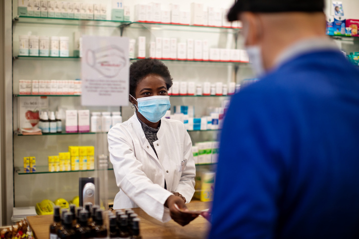 Een slechte Alt-tekst zou zijn: "Apotheker." Beter zou zijn: "Apotheker met mondmasker neemt een papier aan van een klant."