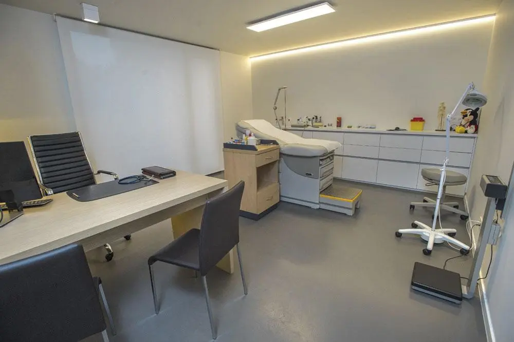 Eén van de drie kabinetten met het gespreksgedeelte uitgewerkt in hout en witte kleur en de onderzoeksruimte in het wit.