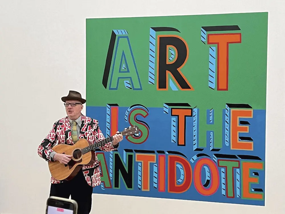 Bob Brill, beter bekend onder het pseudoniem Bob and Roberta Smith, brengt een performance bij zijn kunstwerk Art is the Antidote.