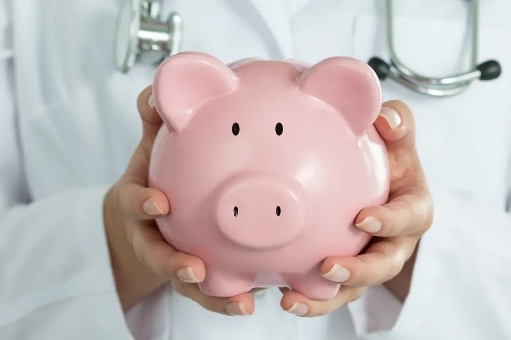 Médecin qui porte une tirelire cochon
