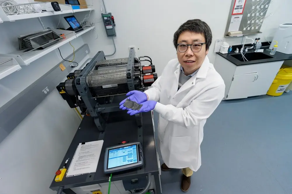 Onderzoeker Minghao Zhang toont het eindresultaat van het droge-elektrodeproces. Het team ontdekte daarbij een unieke interactie tussen bindmiddel en carbonadditief, waardoor een efficiënter geleidingsnetwerk ontstaat en de elektrode stabieler kan functioneren bij hogere spanningen. (Foto: Jason Smith)