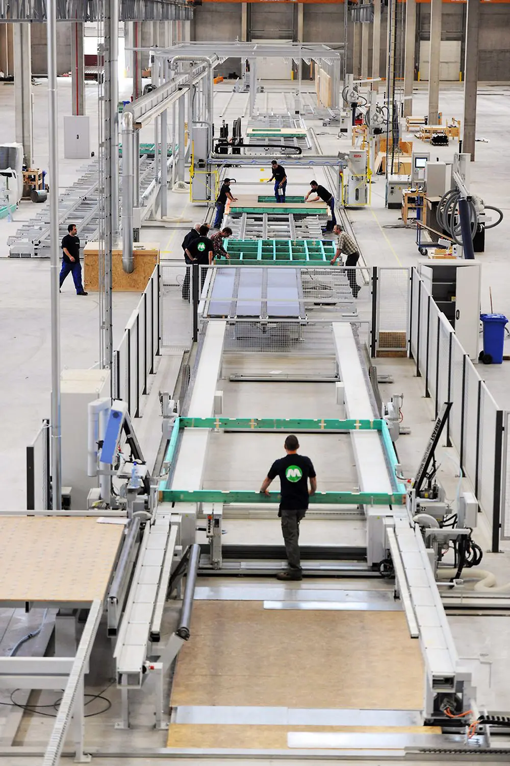 Overzicht van het productieproces, van een leeg frame tot een kant-en-klare wand. Achteraan de lijn is een sluis waarin de wanden met een draaitafel rechtop worden gezet om te worden vervoerd (Bron: Machiels Building Solution)